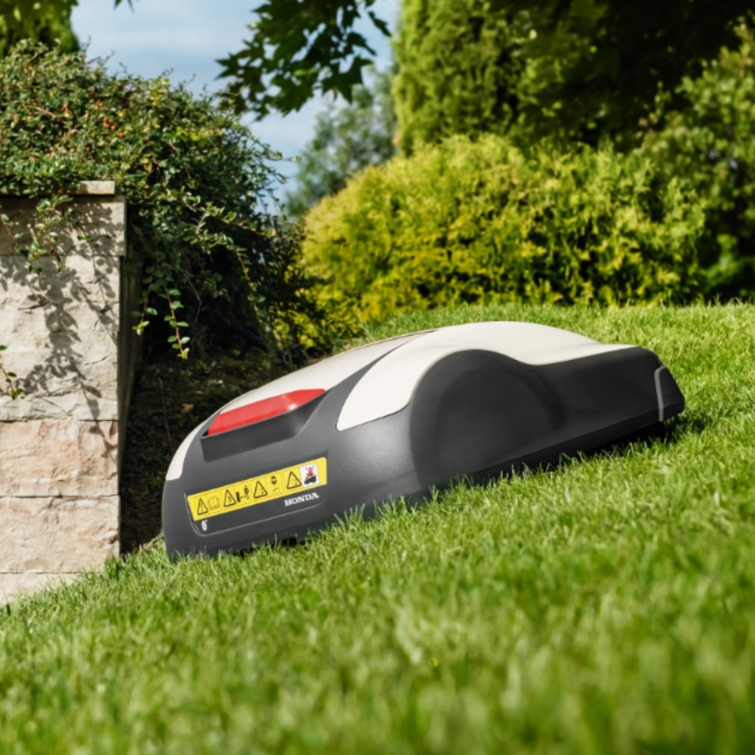 Honda Miimo HRM 1000 robotic lawn mower mowing a sloped lawn, demonstrating reliable performance on uneven garden terrain.