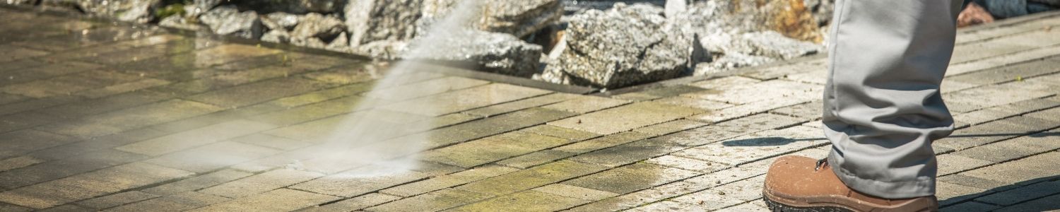 Cleaning patio paving with a pressure washer to remove moss, algae and grime in spring