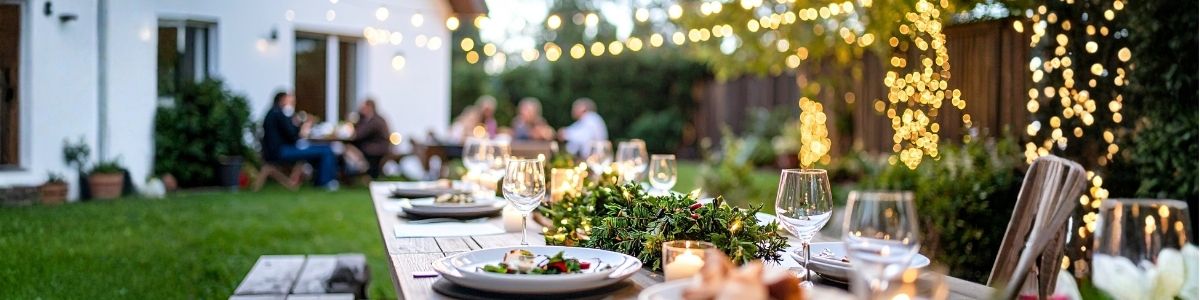 Outdoor garden dining setup with lighting and table decorations, prepared for summer entertaining in a well-maintained garden.