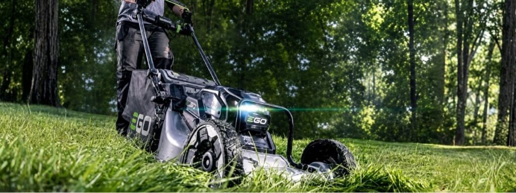 EGO cordless lawn mower cutting long grass in a garden, demonstrating the power and performance of modern battery-powered garden machinery.